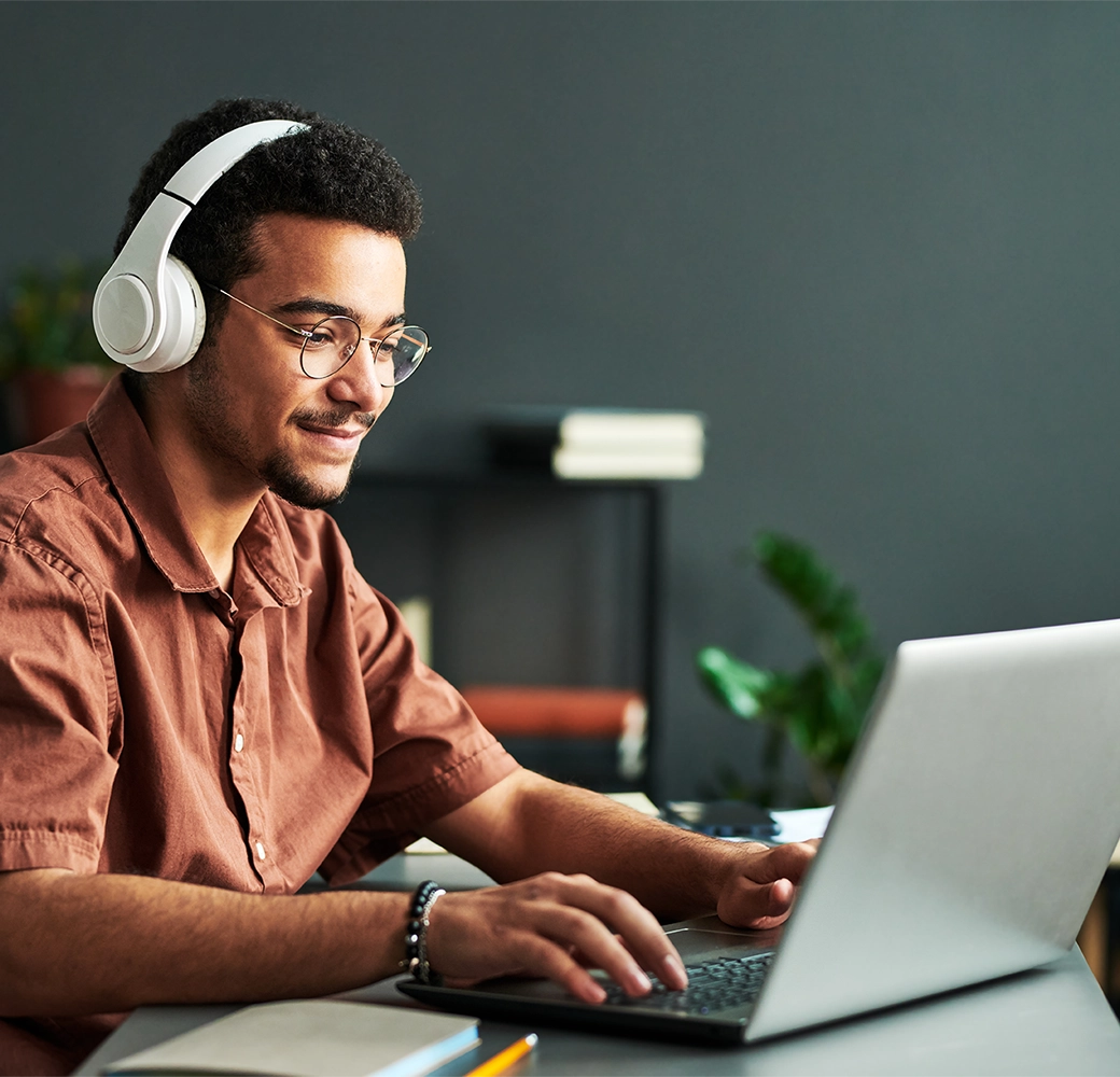 Man wearing headphones and typing on laptop