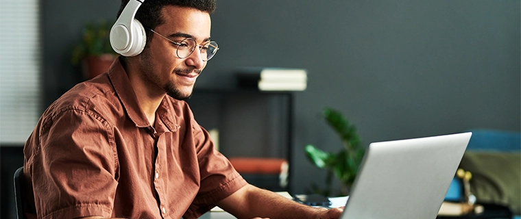 Man wearing headphones and typing on laptop