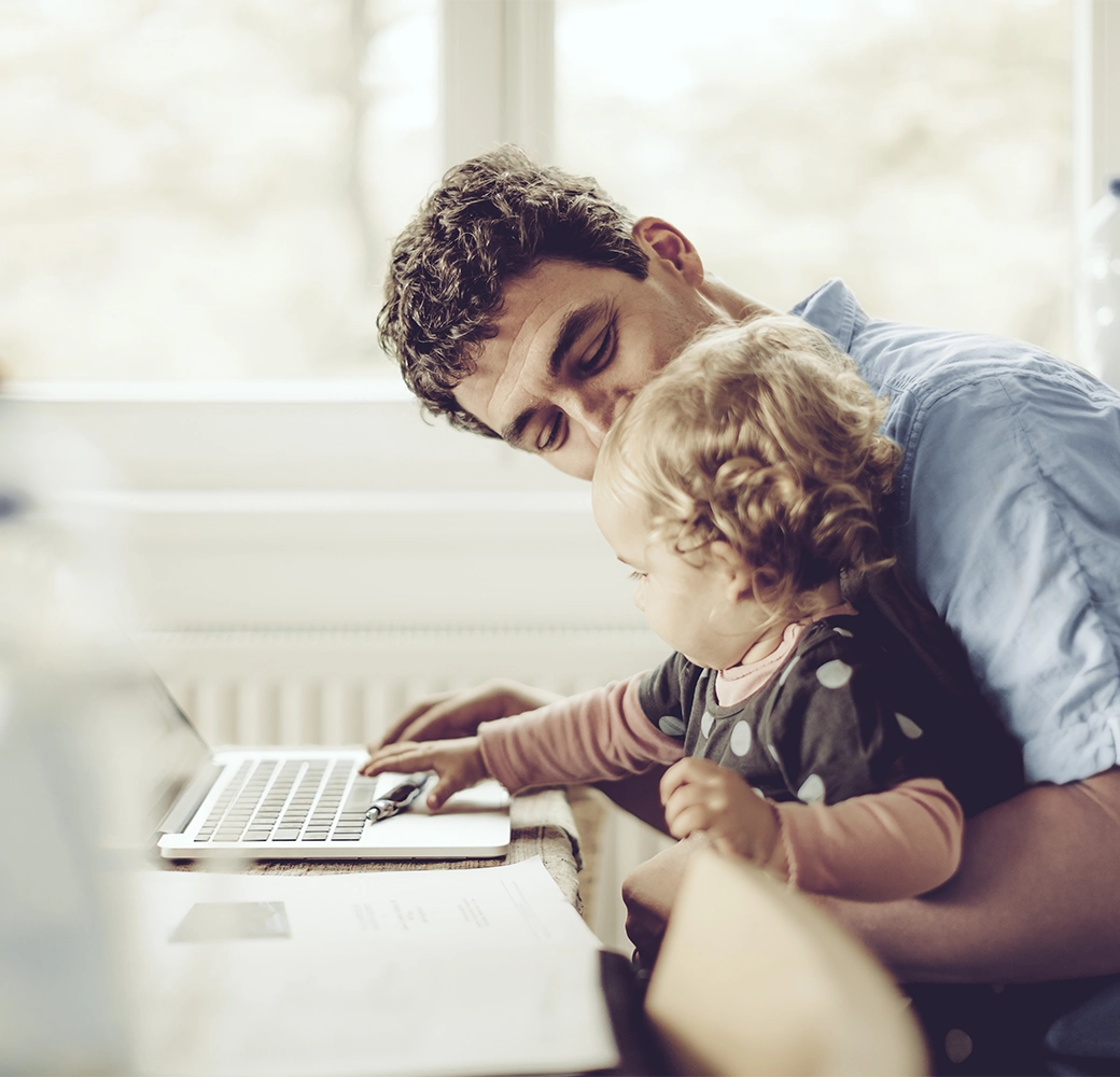 Father holding his baby by his computer