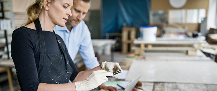 Woman photographing art for business with male coworker overlooking