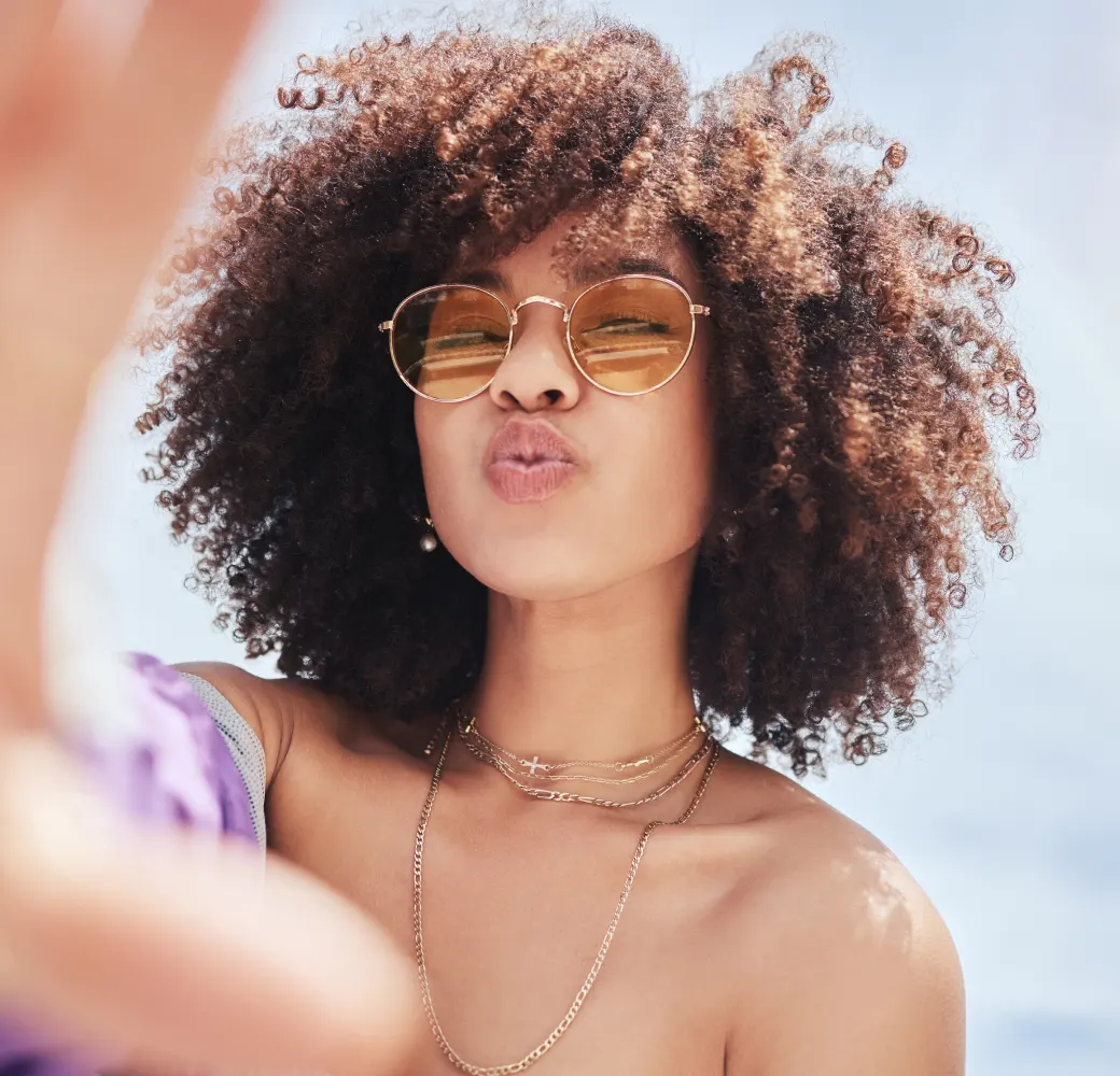 Image of a young woman in sunglasses making a kissy face toward the camera