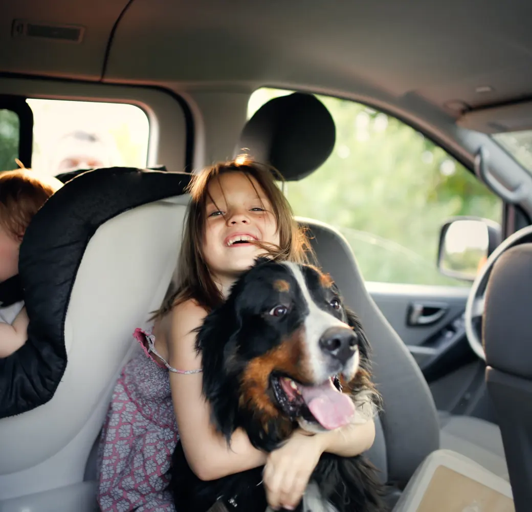 Young girl hugging a dog in a car