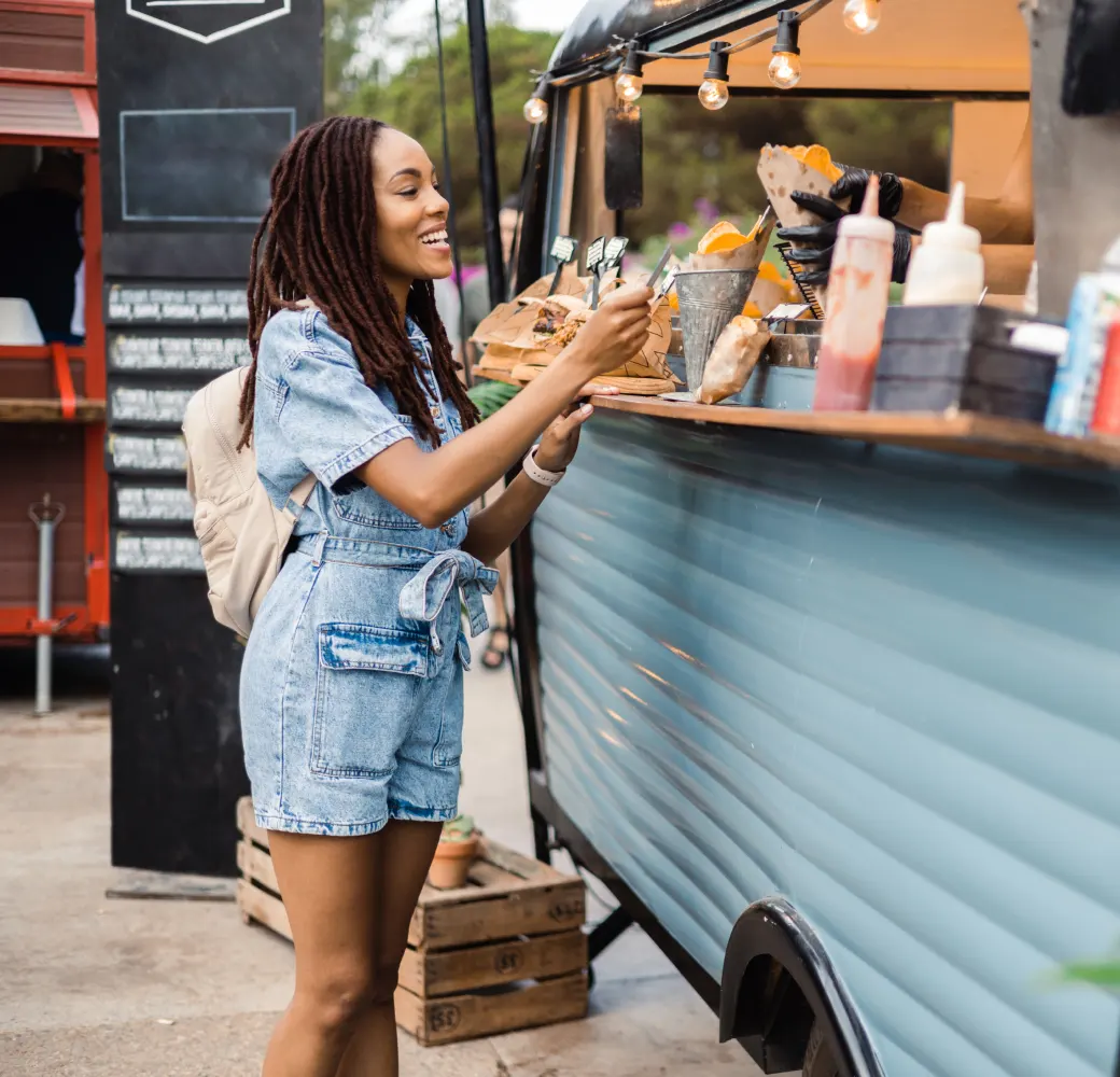 African American woman smiling while buying food from a food truck with her credit card