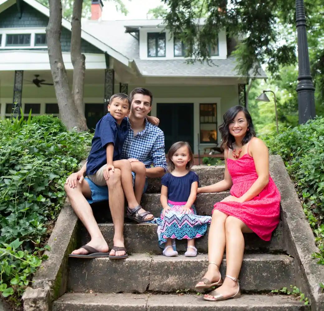 Family of four sitting on steps in front of house