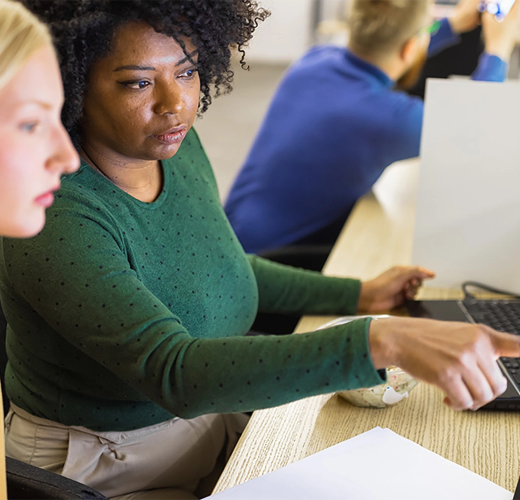 2 women looking and pointing at a computer