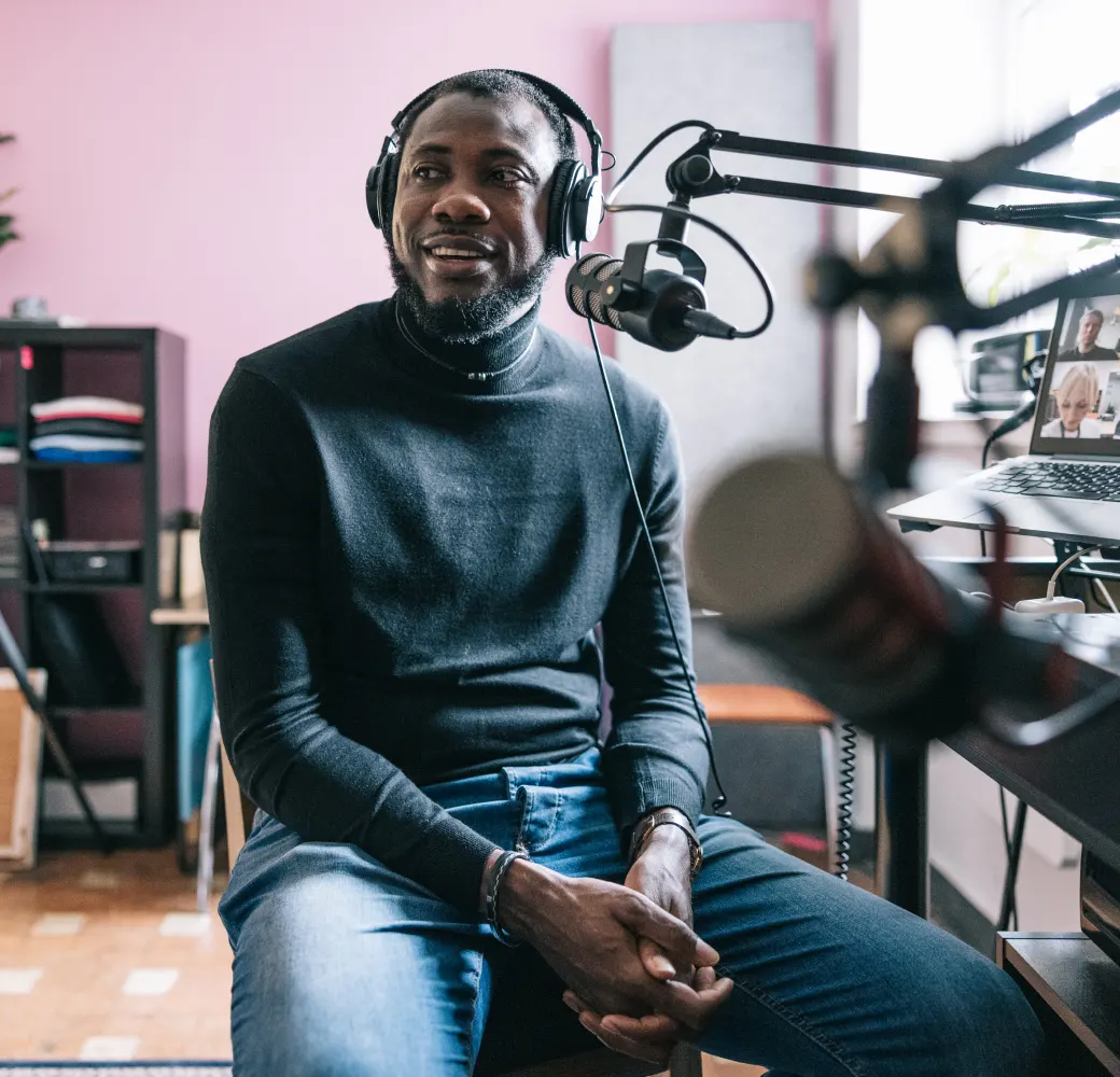 Man sitting in a recording studio smiling and looking off to the side