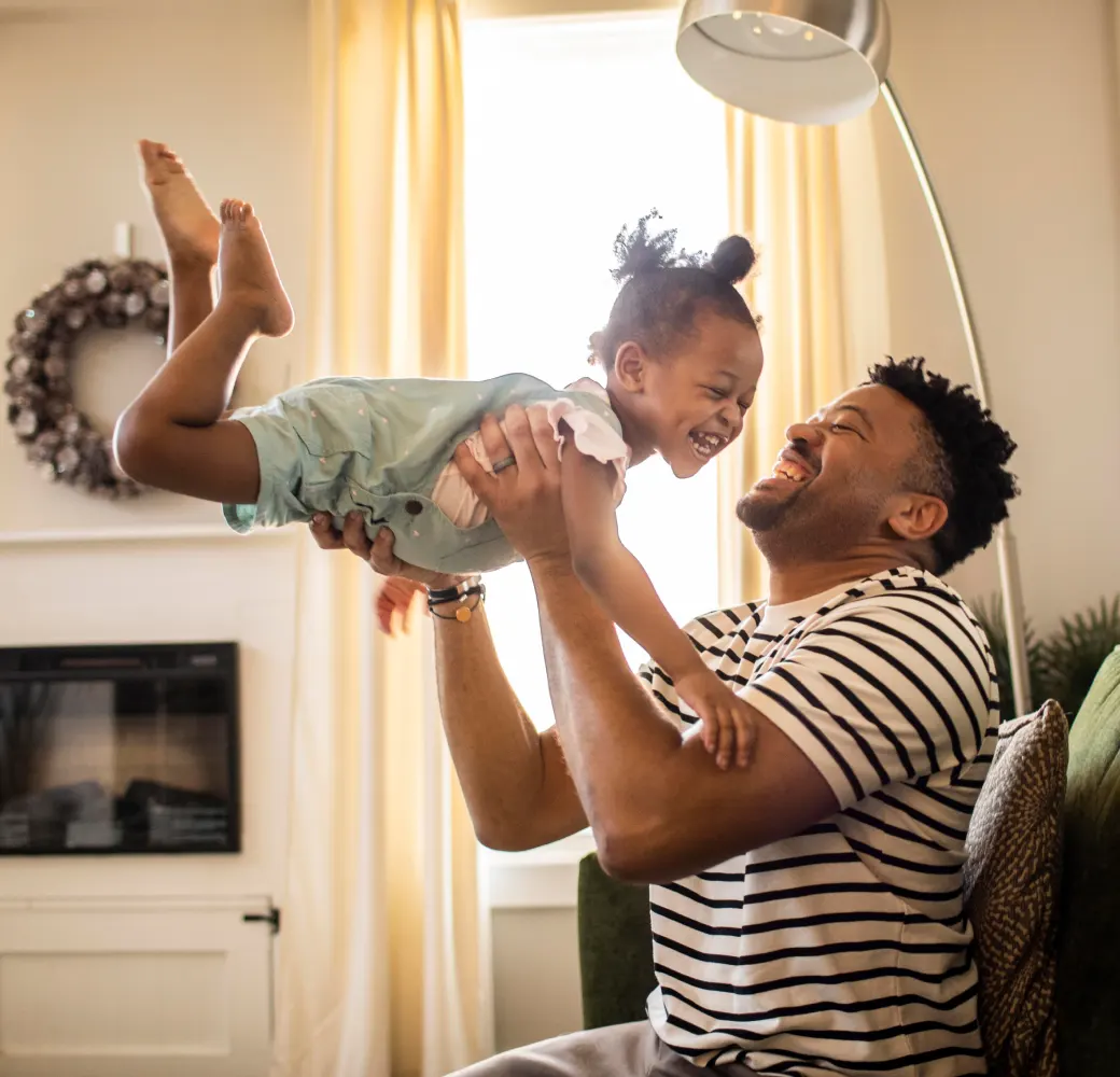 Man swinging a young girl in the air while they laugh