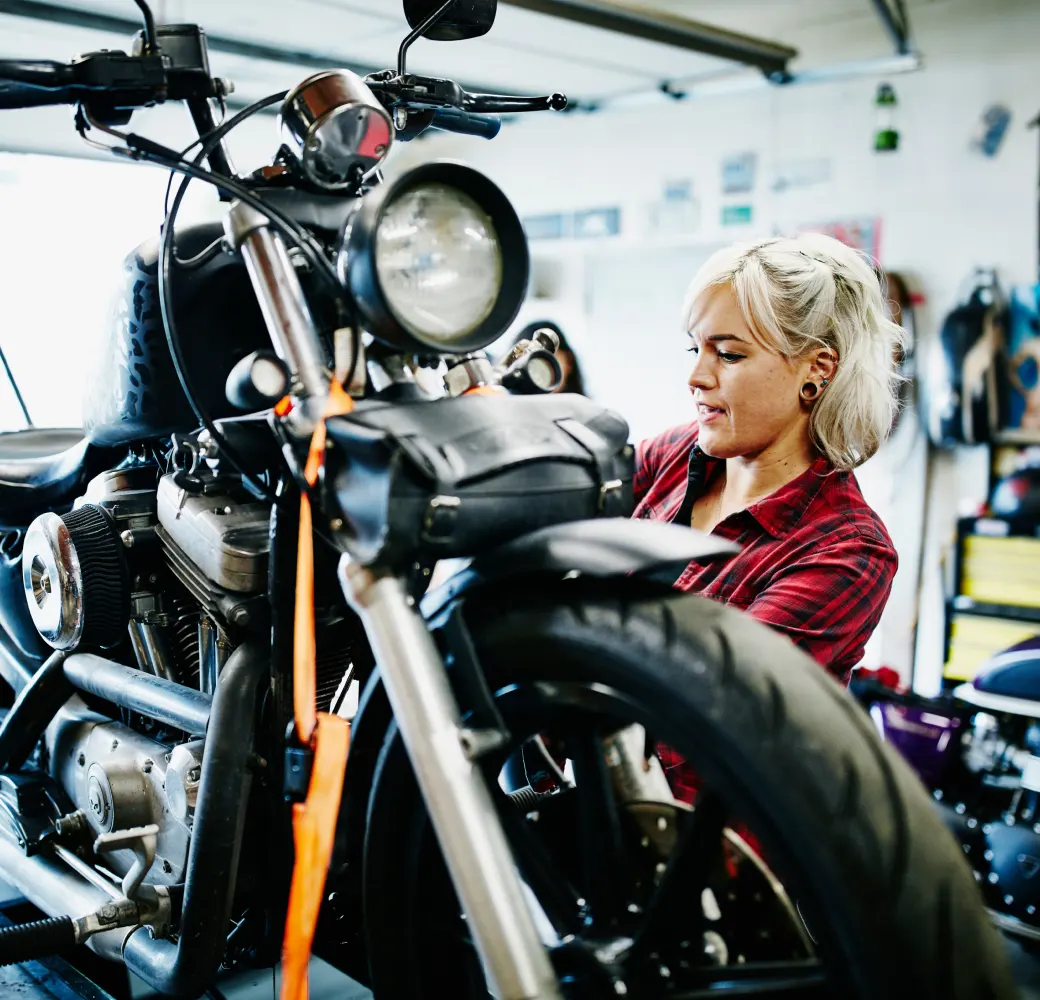 Woman in red flannel shirt repairing a motorcycle