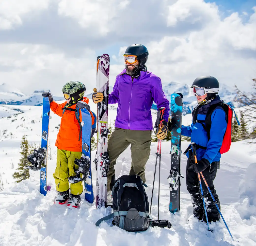 Bearded man with two kids standing on a ski slope together