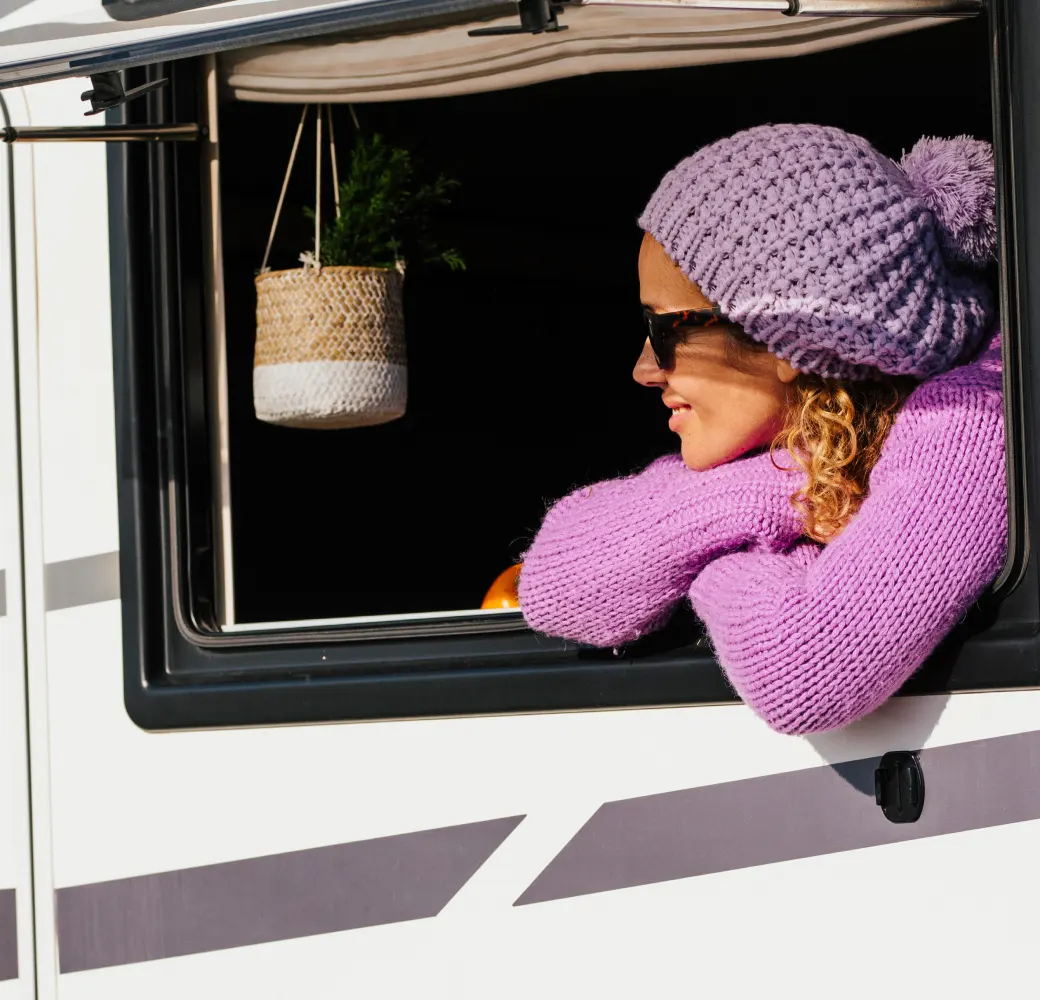 Woman in pink leaning out the window of an RV
