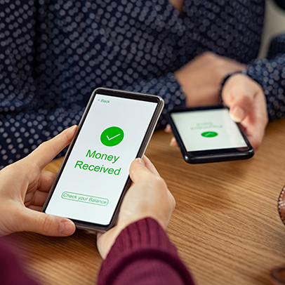 Close up of woman hands holding mobile phone with application to receive money. People holding smart phone and making cashless payment transaction in a shop. Close up of smartphone screen displaying payment sent with money received message.