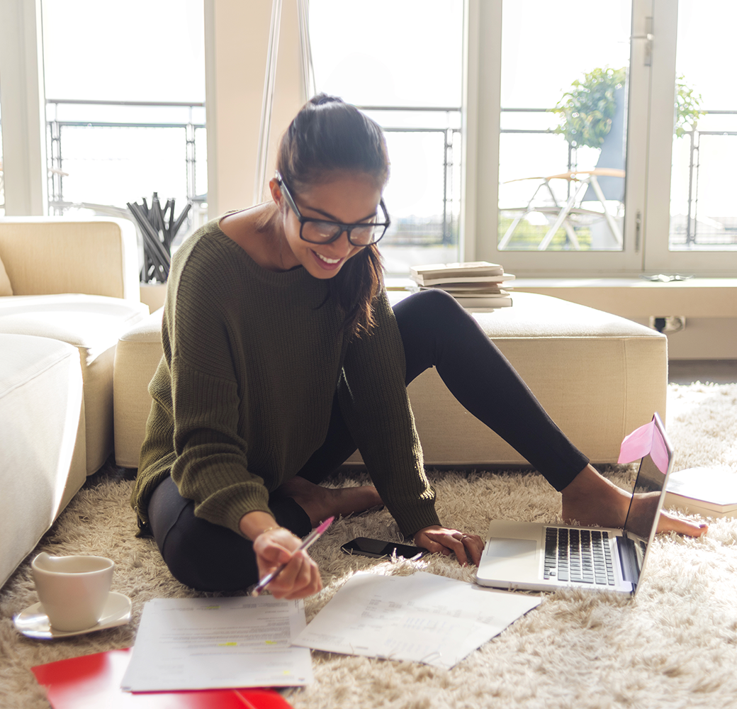 Woman wearing green sweater sitting on floor reviewing papers