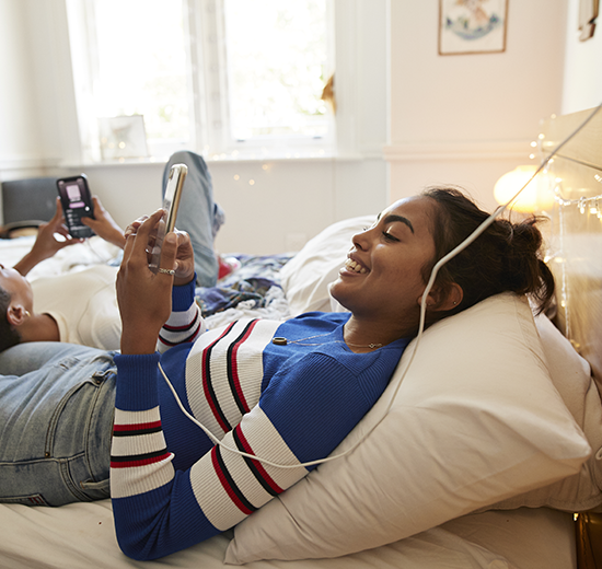 Girl in blue shirt laying on bed with headphones