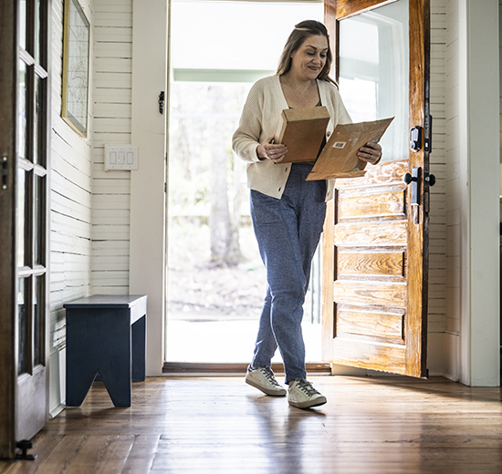 Woman holding mail while walking through door