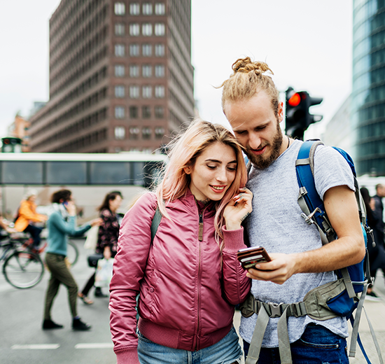 Couple looking at phone while wearing backpacks