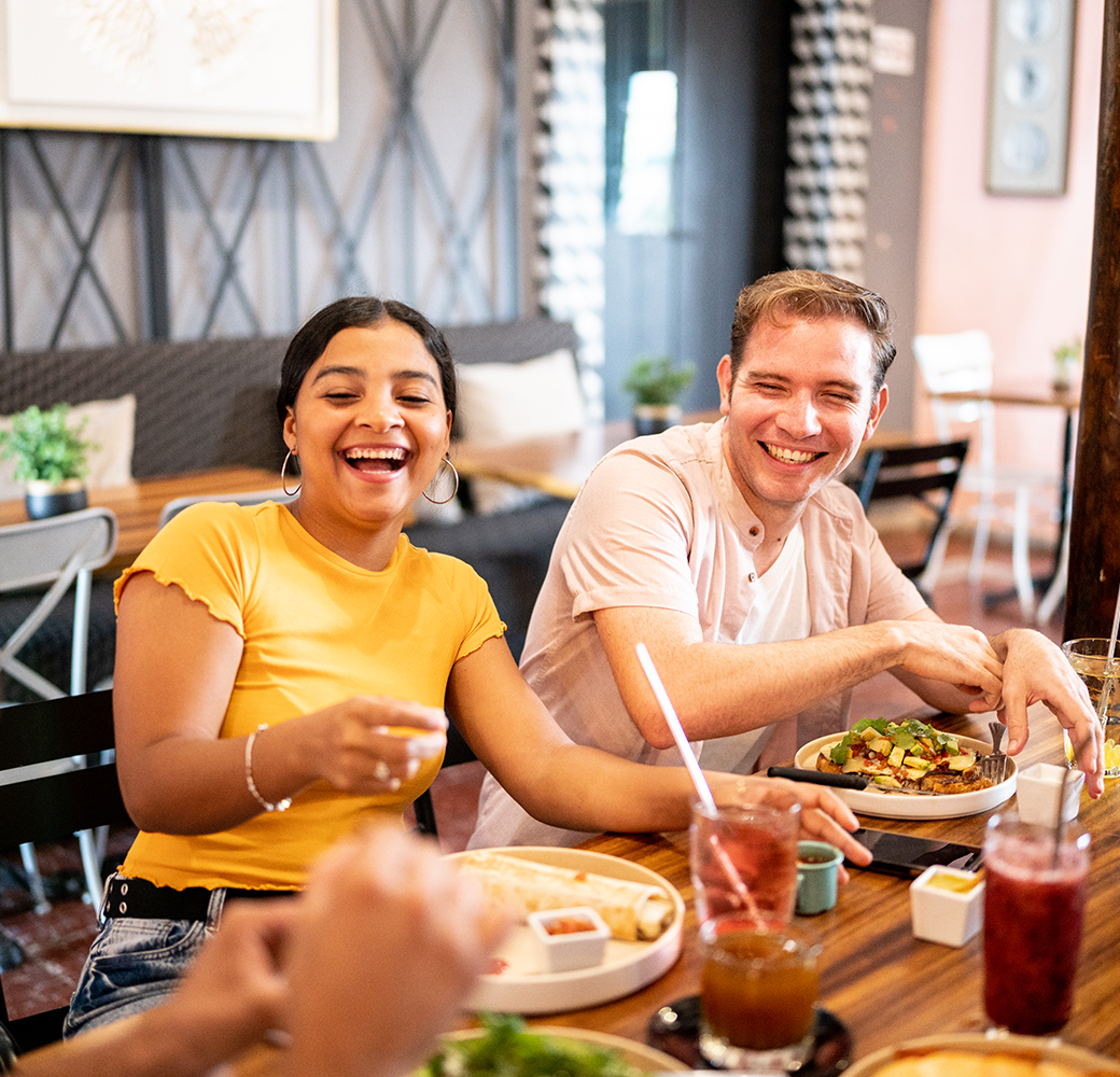 Woman and man sitting at table with food and drinks in front of them