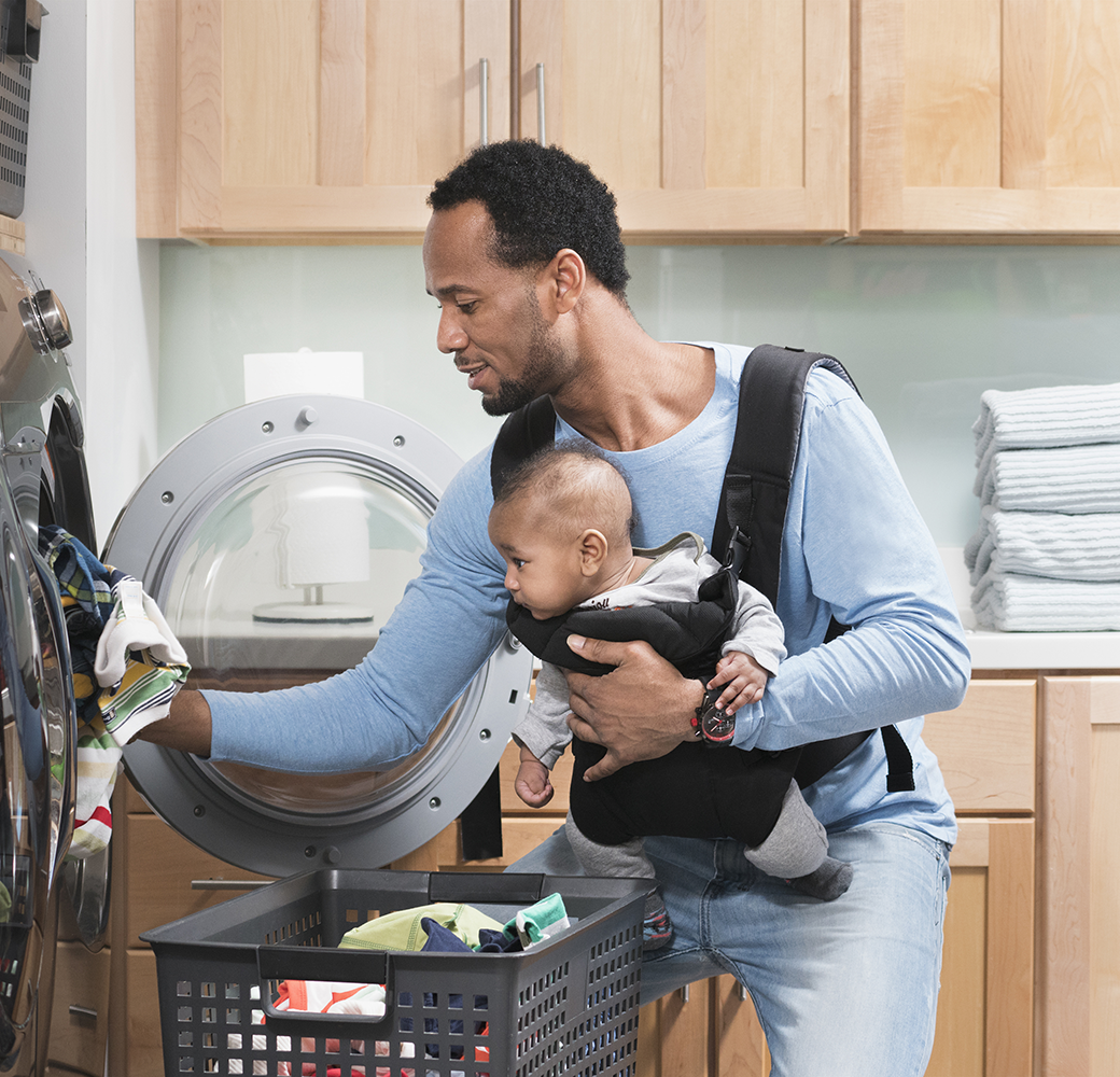 Man doing laundry with baby in carrier