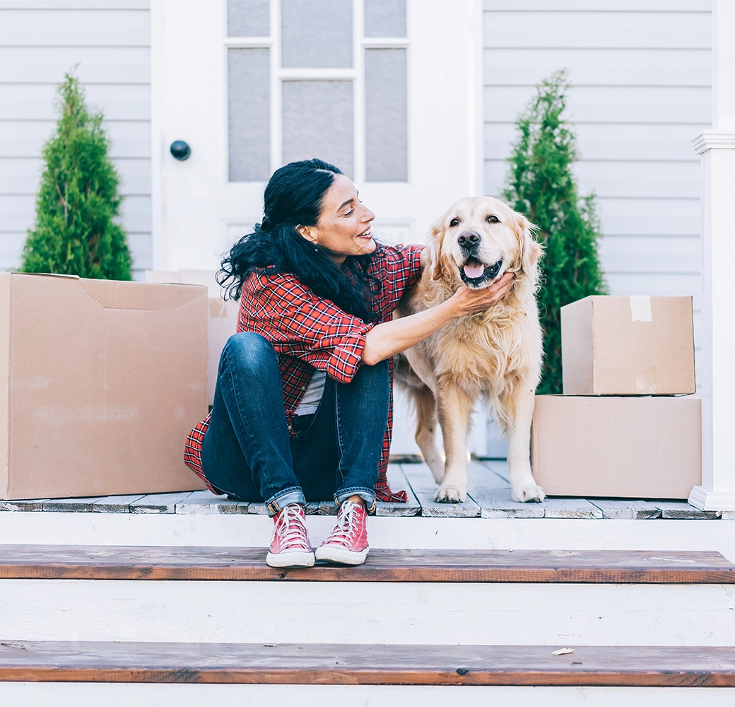 Woman sitting outside of her house and petting her dog