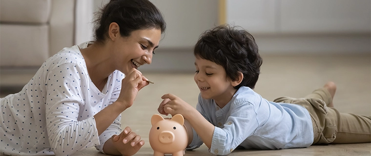 Mother and son putting money into a piggy bank