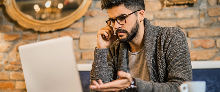 Angry man talking on the phone and pointing at his computer