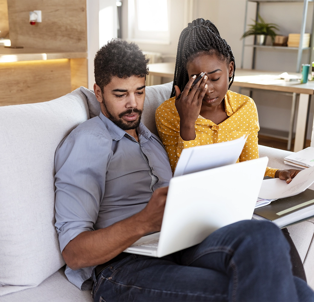 Frustrated couple looking at computer and paperwork