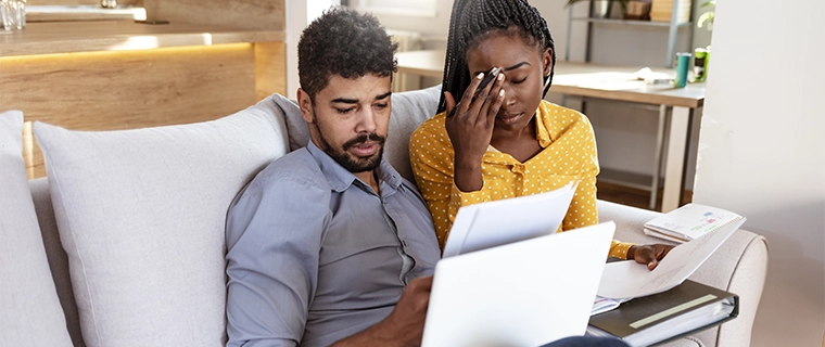 Frustrated couple looking at computer and paperowrk