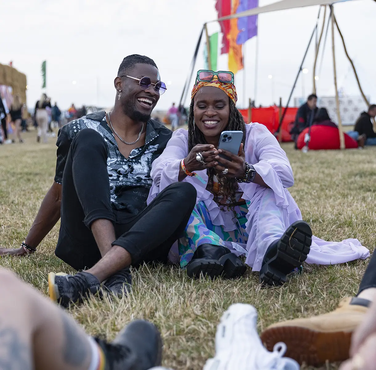 Two friends sitting together on the ground at a festival