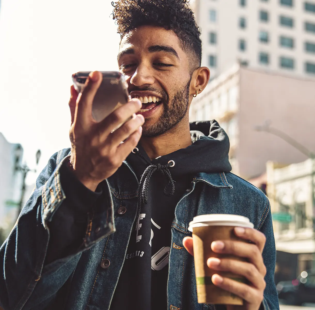 Man holding coffee while on phone