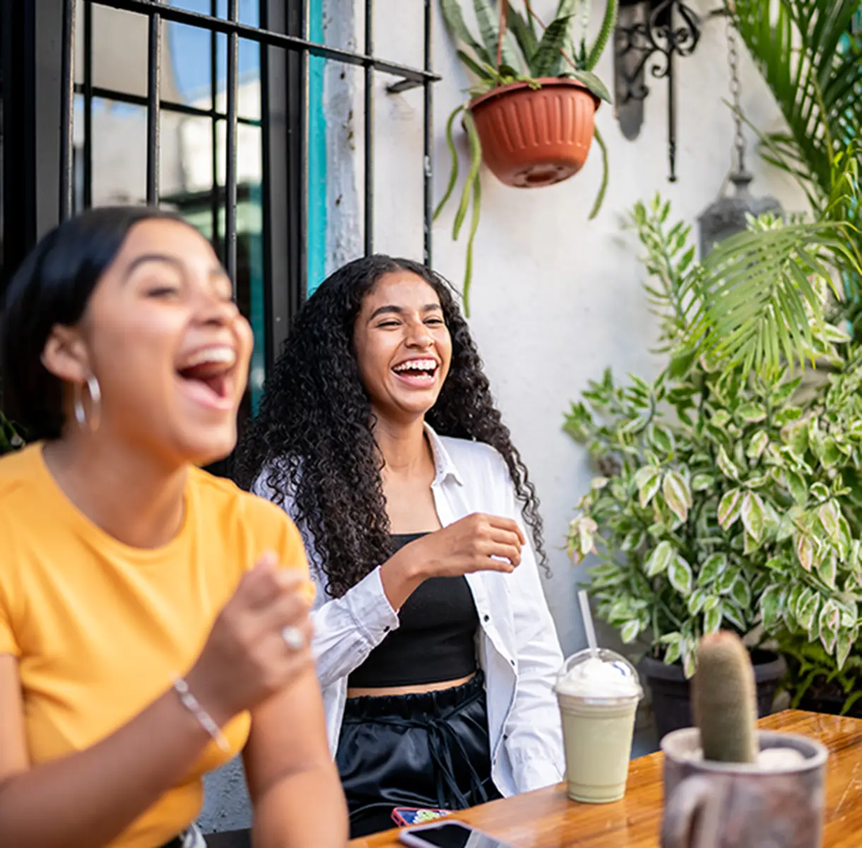 Two women laughing while having frappucinos