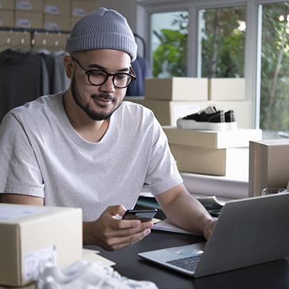 Asian man online seller confirming orders from customer on the phone. E-commerce male business owner looking at the phone in store warehouse.