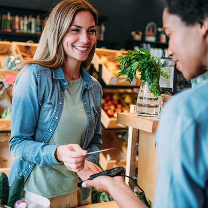 Shot of a female customer making wireless or contactless payment using debit or credit card. Woman paying for groceries at checkout in organic store.