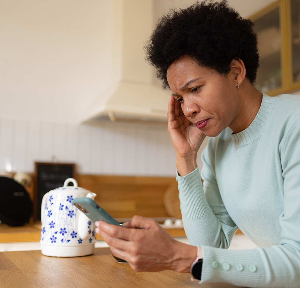 Black woman on phone while in kitchen expressing concern