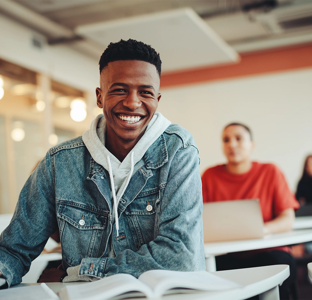 Student sitting in class and smiling at the camera