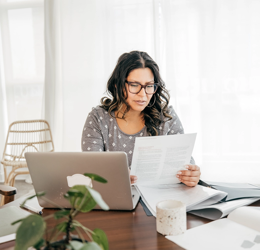 Woman holding a piece of paper by her computer