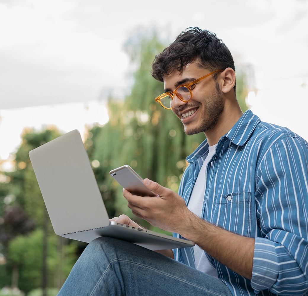 Man looking at cell phone and laptop