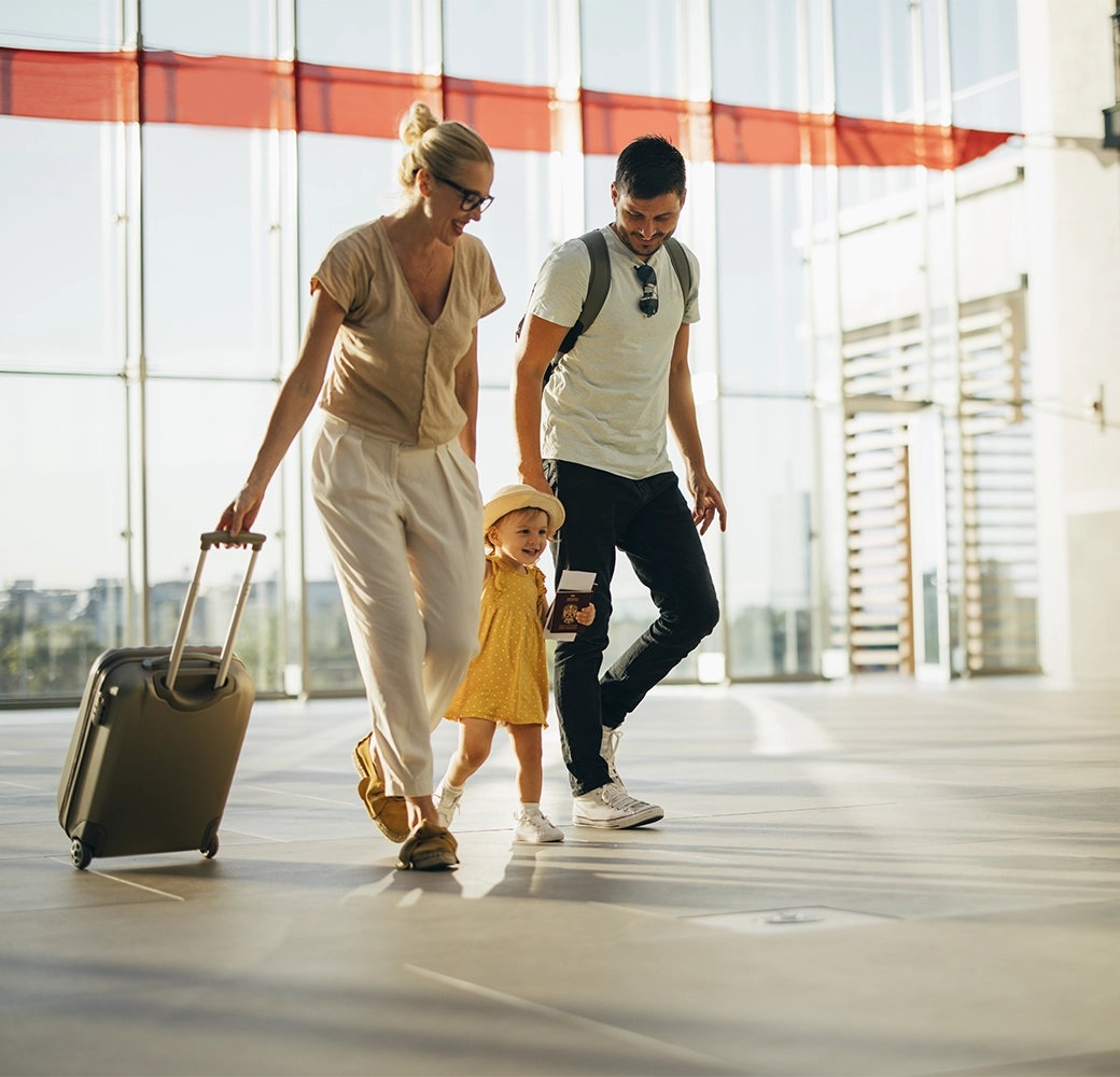 Family walking through airport with carry on suitcase