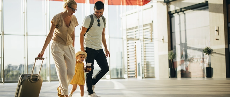 Family walking through airport with carry on suitcase